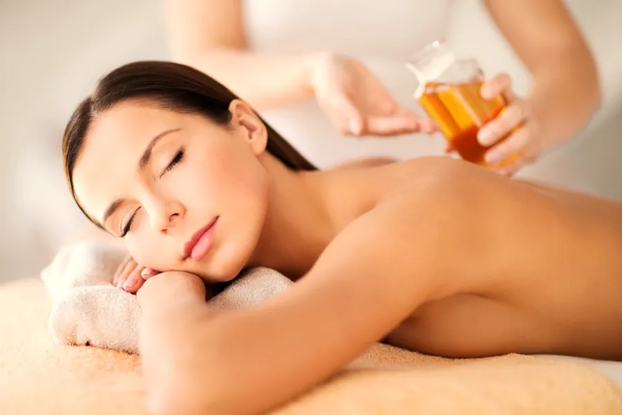 Eine Frau liegt entspannt auf der Massageliege, während warmes Öl aufgetragen wird
